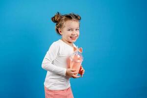 retrato de un pequeño contento niña de eslavo apariencia Bebiendo un cóctel de bayas. sitio para texto foto