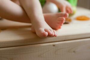 baby's feet on a wooden table with fruit close-up photo