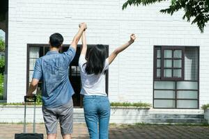 contento Pareja en frente de el nuevo hogar en Moviente en día, y comienzo un nuevo vida familia. concepto de dueño de casa y reubicación foto