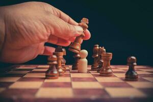 Close up of hands confident businessman moving chess figure in competition success play. the chess game is development analysis, strategy, and plan, the management or leadership concept. photo