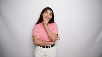 Thoughtful young woman is wearing pink shirt while looking aside in Studio with White background video
