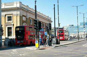 Beautiful Low Angle View of Central London and Road with Traffic and People. The Image Was Captured at Tower Bridge London England Great Britain on Warm Sunny Day of 04-June-2023 photo