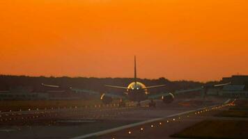 The wide bodied aircraft lands on the illuminated runway in the early morning video