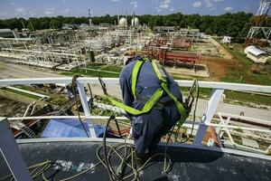 atención masculino trabajador cuerda acceso altura la seguridad inspección de almacenamiento petróleo y gas tanque foto