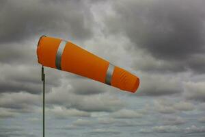 Windsock indicator of wind on tank chemical cone indicating wind direction and force. Horizontally flying windsock with cloud sky photo