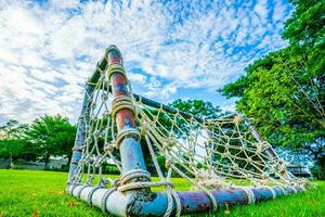 Rope net goal, mini soccer field with green grass Simple, old-fashioned miniature mosquito nets woven with straw clutter up the park sky and white clouds background, selective focus, soft focus. photo