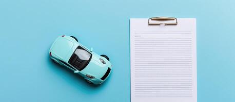 A blue toy car next to a paper with a pen on it created with technology photo