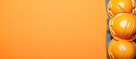 Three yellow hard hats sitting on top of an orange background created with technology photo