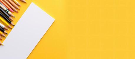 A yellow background with colored pencils and a piece of paper created with technology photo