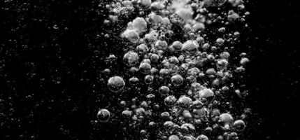 Soda water bubbles splashing underwater against black background. photo