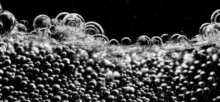 Soda water bubbles splashing underwater against black background. photo