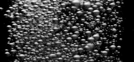 Soda water bubbles splashing underwater against black background. photo