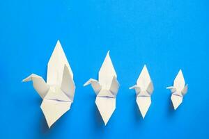 white bird origami paper on blue background. bird peace, freedom or opportunities concept photo