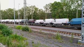 Dusseldorf Germany 06 11 2023 Goods train transporting many transporter cars on rails with many trucks and vans on fright train or goods train delivers new transporters throughout the whole country video