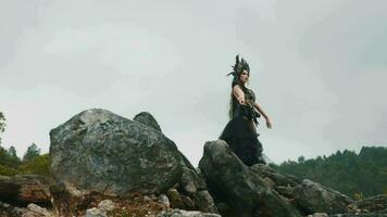 un bruja en un negro vestido y corona bailes en un rock en un montaña video