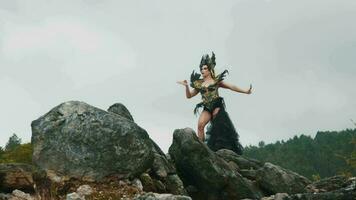 ein Hexe im ein schwarz Kleid und Krone Tänze auf ein Felsen im ein Berg video