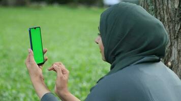 posteriore Visualizza di giovane donna utilizzando inteligente Telefono con verde schermo seduta su parco video