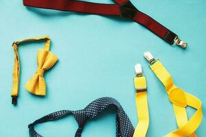 men's ties, suspenders and bow ties on blue background with copy space. father's day concept photo