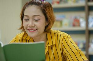 young woman sitting happily reading a book in the library photo