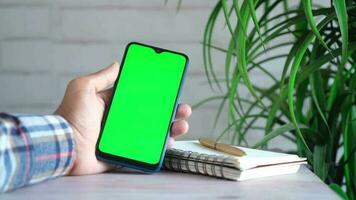 Feche a mão do jovem usando um telefone inteligente com tela verde video