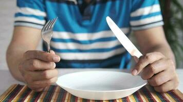 Hand holding cutlery with empty plate on wooden table video
