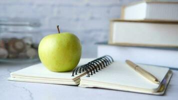 concepto de regreso a la escuela con manzana en el bloc de notas en la mesa video