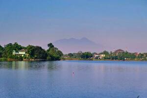 view of the lake with the silhouette of a mountain in the background photo