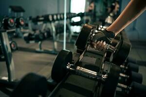 Close-up woman hands lifting dumbbells at gym. photo