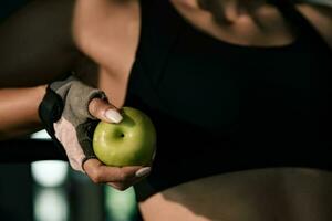 Close-up hands woman holding apple fruit after exercise workout in gym. photo