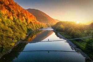 Aerial view of silhouette of walking man on the suspension bridge photo