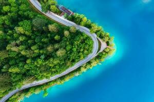 Aerial view of road near blue lake, forest at sunrise in summer photo