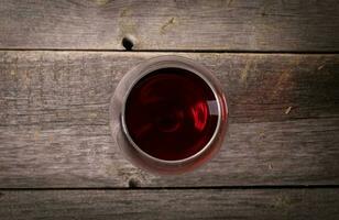 Glass of red wine on wooden table. View from top photo