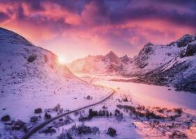 Aerial view of snowy mountains, road, houses and purple sky photo