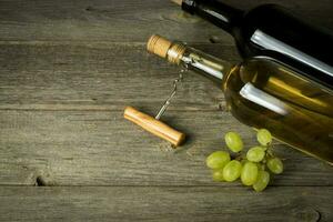 Glass bottle of wine with corks on wooden table background photo