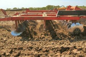 The tractor plows the soil with a cultivator smashing clods in t photo