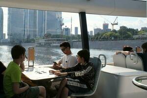 Passengers on a board of aquabus boat on Moskva River. Electrical ship. Ecological public transport . Green energy in city route. Daily passenger ferry service. Moscow, Russia - June 22, 2023. photo