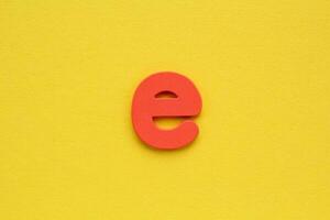 Wooden red letter E on yellow background. Alphabet concept photo
