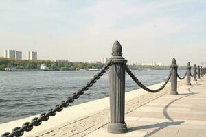 Metal chains of the bank fence of the river embankment on the background of the water surface photo