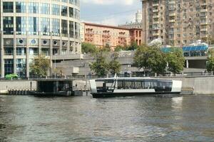 Aquabus boat on Moskva River. Electrical ship at Moscow public transport. Ecological technology. Green energy in city route. Daily passenger ferry service. Moscow, Russia - June 22, 2023. photo
