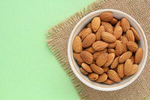 Almond nuts on canvas and green background. Healthy diet, nutrition concept. Protein dry organic snack. Raw vegetarian food. World vegan day photo