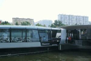 Aquabus boat on Moskva River. Electrical ship at Moscow public transport. Ecological technology. Green energy in city route. Daily passenger ferry service. Moscow, Russia - June 22, 2023. photo