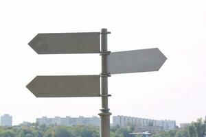 Signpost arrow pointers at public park city. Blank direction signs on a metal column photo