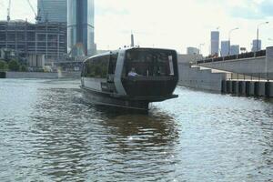 Aquabus boat on Moskva River. Electrical ship at Moscow public transport. Ecological technology. Green energy in city route. Daily passenger ferry service. Moscow, Russia - June 22, 2023. photo