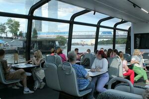 Passengers on a board of aquabus boat on Moskva River. Electrical ship. Ecological public transport . Green energy in city route. Daily passenger ferry service. Moscow, Russia - June 22, 2023. photo