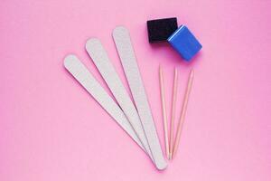 Different abrasive nail polishing files and wooden sticks on pink background. Manicure and pedicure instruments set . Cosmetic accessories hygiene equipment. Beauty spa salon, hand care concept photo