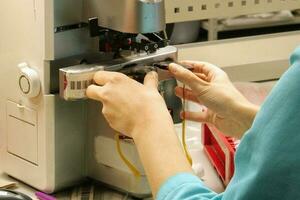 Factory for making spectacle lenses and frames, myopia glasses, sunglasses, production line. Close-up of technician manufacturing lens. Hands of a master in optics salon and repair shop photo