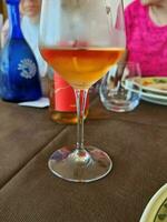 vaso de Rosa vino con un borroso antecedentes en un restaurante en el ligur riviera durante un almuerzo en un verano domingo en junio 2023 foto