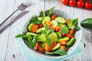 Diet salad of cucumbers, tomatoes and mint in a bowl on the table photo