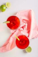 Alcoholic cosmopolitan cocktail in glasses and lime on the table top and vertical view photo