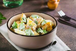 Potato salad in a peel with parsley and mayonnaise in a bowl on the table photo